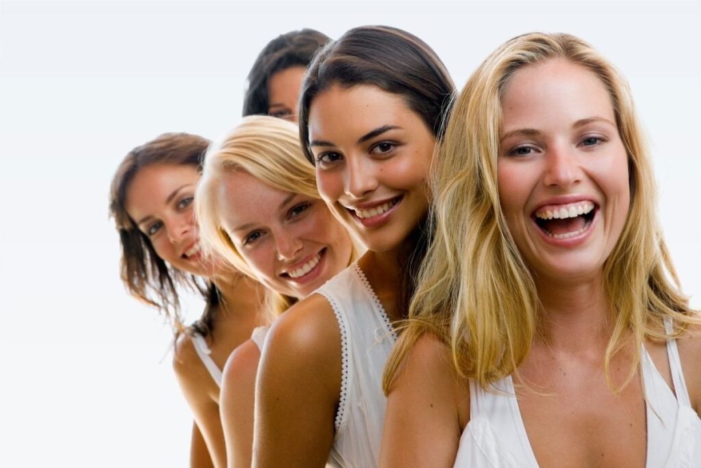 Group of five smiling women outdoors in white tops, conveying joy and friendship while addressing common IV therapy myths about wellness treatments.