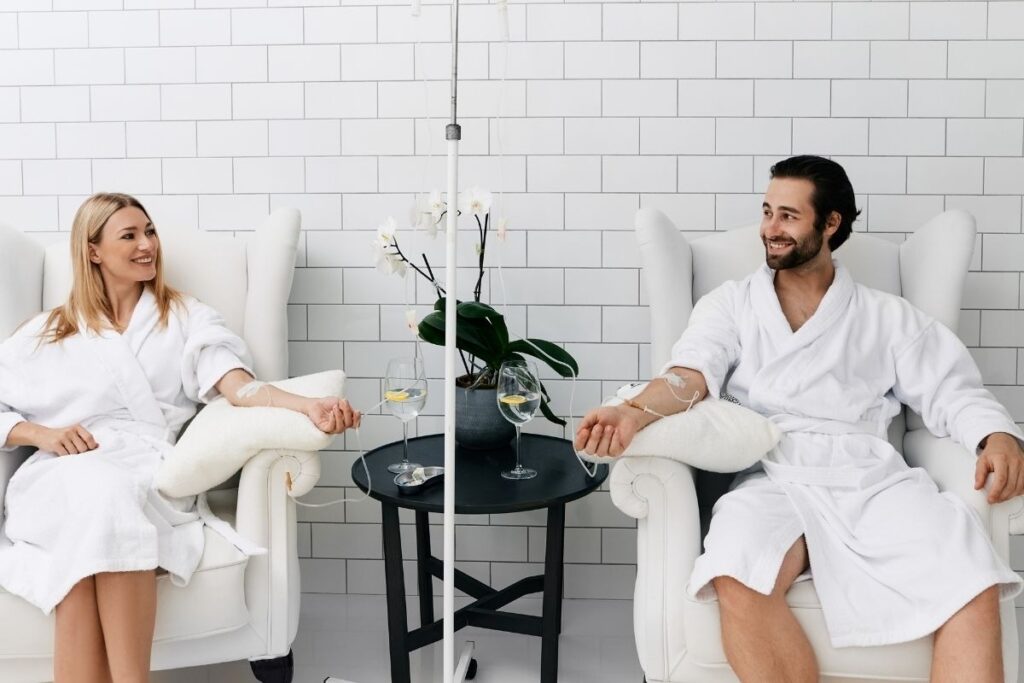 Two clients relaxing and receiving IV Therapy for Hydration in a comfortable wellness clinic.