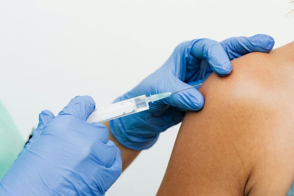 Medical professional giving an intramuscular vitamin shot as part of vitamin therapy delivery methods.